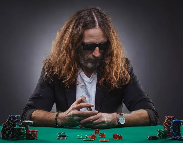 Bello dai capelli lunghi che gioca a poker in un casinò . — Foto Stock