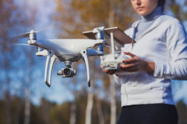 Adam quadrocopter uçuş kontrol eder. Helikopter uçuyor. Bir kadın elinde uzaktan kumanda