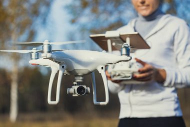 Adam quadrocopter uçuş kontrol eder. Helikopter uçuyor. Bir kadın elinde uzaktan kumanda
