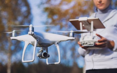 Adam quadrocopter uçuş kontrol eder. Helikopter uçuyor. Bir kadın elinde uzaktan kumanda