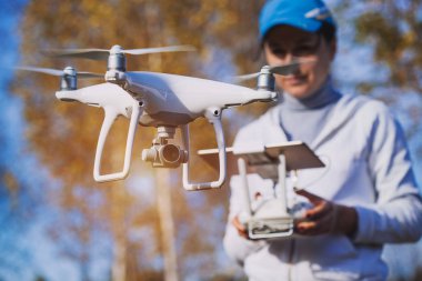 Adam quadrocopter uçuş kontrol eder. Helikopter uçuyor. Bir kadın elinde uzaktan kumanda