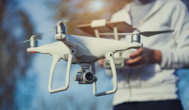 Adam quadrocopter uçuş kontrol eder. Helikopter uçuyor. Bir kadın elinde uzaktan kumanda
