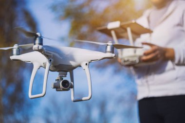 Adam quadrocopter uçuş kontrol eder. Helikopter uçuyor. Bir kadın elinde uzaktan kumanda