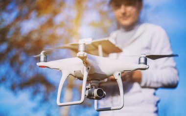 Adam quadrocopter uçuş kontrol eder. Helikopter uçuyor. Bir kadın elinde uzaktan kumanda