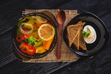 Siyah ahşap arka plan üzerinde bir tencerede taze sebze çorbası