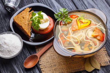 Siyah ahşap arka plan üzerinde bir tencerede erişte ile taze sebze çorbası