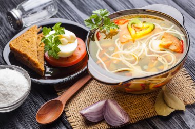 Siyah ahşap arka plan üzerinde bir tencerede erişte ile taze sebze çorbası