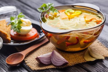 Siyah ahşap arka plan üzerinde bir tencerede erişte ile taze sebze çorbası