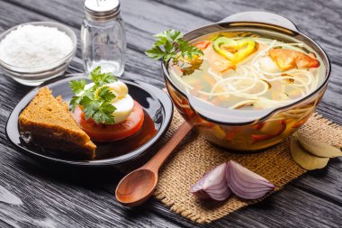 Siyah ahşap arka plan üzerinde bir tencerede erişte ile taze sebze çorbası