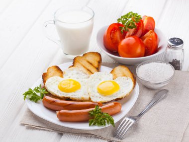 Sevgililer günü - bir kalp ve sosis, süt, Beyaz ahşap masa üzerinde domates şeklinde kızarmış yumurta kahvaltı.