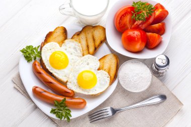 Sevgililer günü - bir kalp ve sosis, süt, Beyaz ahşap masa üzerinde domates şeklinde kızarmış yumurta kahvaltı.