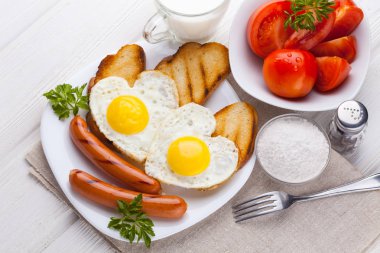 Sevgililer günü - bir kalp ve sosis, süt, Beyaz ahşap masa üzerinde domates şeklinde kızarmış yumurta kahvaltı.