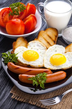Sevgililer günü - bir kalp ve sosis, süt, siyah ahşap masa üzerinde domates şeklinde kızarmış yumurta kahvaltı.