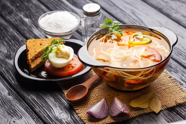 Siyah ahşap arka plan üzerinde bir tencerede erişte ile taze sebze çorbası