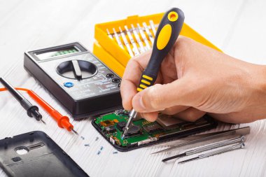 Onarım ve beyaz bir tabloda bir multimetre ile test smartphone