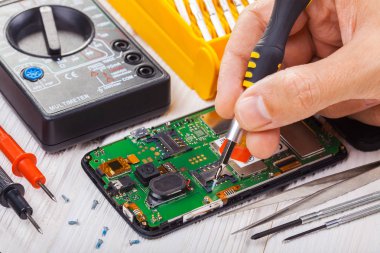 Onarım ve beyaz bir tabloda bir multimetre ile test smartphone