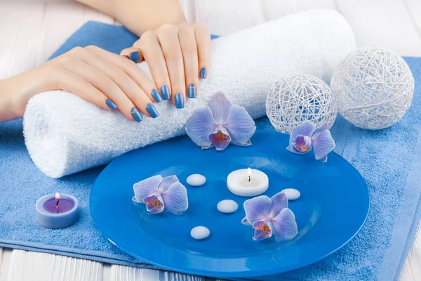 美丽的蓝色美甲装饰 兰花和毛巾在白色的木桌上 — 图库照片