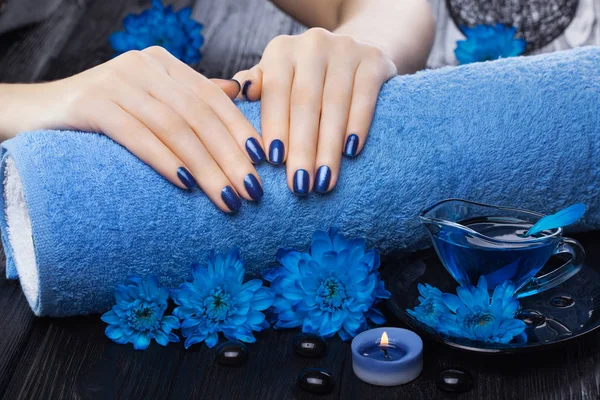 美丽的蓝色美甲与油和蜡烛 菊花和毛巾在黑色的木桌上 — 图库照片