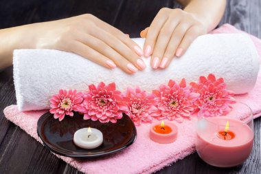 Petrol ve mumlar, krizantem ve siyah ahşap masa havluda güzel pembe manikür. Spa