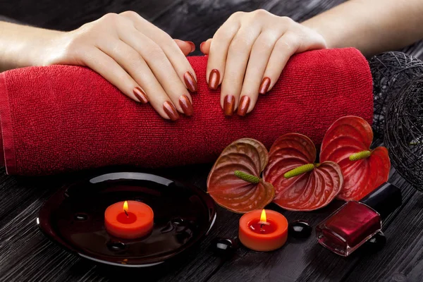 油とキャンドル 赤いカラーの花黒の木製のテーブルにタオルと美しい赤いマニキュア — ストック写真