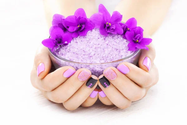 beautiful purple manicure with violet, candle and sea salt on the white wooden table. spa