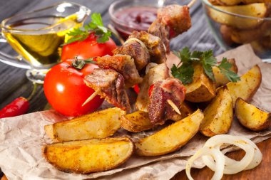 Soğan, fırında patates, domates ve yeşillik siyah ahşap masa üzerinde otlar ile et şiş