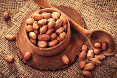 Eski bir çuval bezi üzerinde ahşap bir kasede soyulmuş fıstık. rustik tarzı