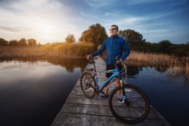 bisikleti. adam ahşap bir köprüde Nehri Rides.
