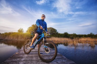 bisikleti. adam ahşap bir köprüde Nehri Rides.