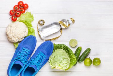 Fitness, aktif yaşam tarzları kavramı. Taze sağlıklı sebze, spor ayakkabı Beyaz ahşap zemin üzerinde. metin için yer kopyalayın. Üstten Görünüm