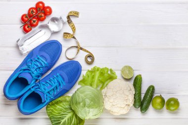 Fitness, aktif yaşam tarzları kavramı. Taze sağlıklı sebze, spor ayakkabı Beyaz ahşap zemin üzerinde. metin için yer kopyalayın. Üstten Görünüm