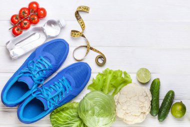 Fitness, aktif yaşam tarzları kavramı. Taze sağlıklı sebze, spor ayakkabı Beyaz ahşap zemin üzerinde. metin için yer kopyalayın. Üstten Görünüm