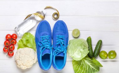 Fitness, aktif yaşam tarzları kavramı. Taze sağlıklı sebze, spor ayakkabı Beyaz ahşap zemin üzerinde. metin için yer kopyalayın. Üstten Görünüm