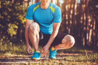 Runner üzerinde spor ayakkabı ayakkabı bağcığı bağlama. Ormanda koşu sabah