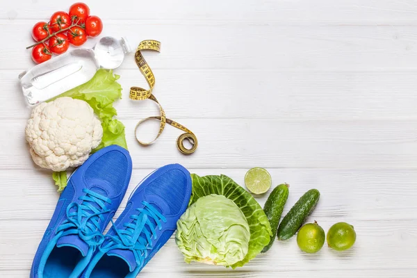 Fitness, active lifestyles Concept. Fresh healthy vegetables, sport shoes on white wood background. copy space for text. Top view