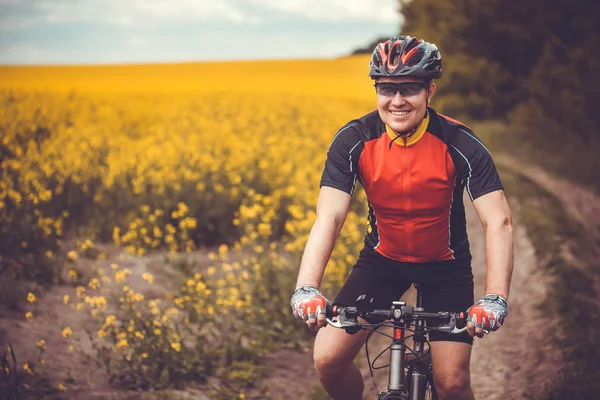 男性サイクリストは 美しい黄色の菜種フィールドに乗っています スポーツ レジャー — ストック写真