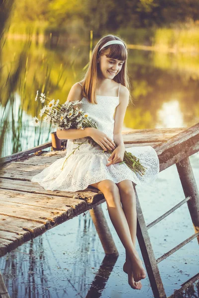 幸せな少女は 開花鎮静の花束と橋の上の小さな川を賞賛します — ストック写真