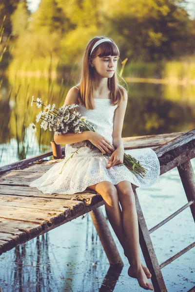 幸せな少女は 開花鎮静の花束と橋の上の小さな川を賞賛します — ストック写真