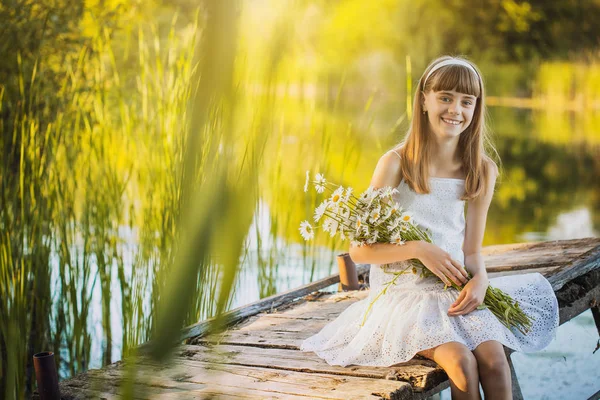 幸せな少女は 開花鎮静の花束と橋の上の小さな川を賞賛します — ストック写真