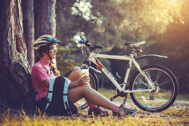 kadın bir ağacın altında istirahat ve içme su bisikletçi. Macera turizmi.