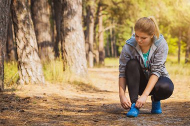 kadın Runner bağlama ayakkabı bağcığı spor ayakkabılar üzerinde. Ormanda koşu sabah. Fitness