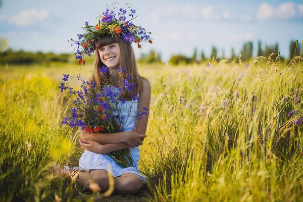 幸せな女の子の野生の花の花束と夕日の草原 — ストック写真