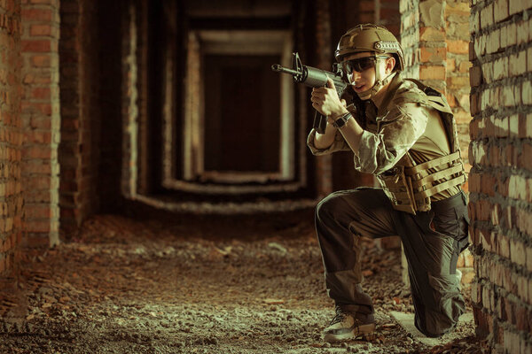 airsoft soldier with a rifle playing strikeball In an abandoned brick building