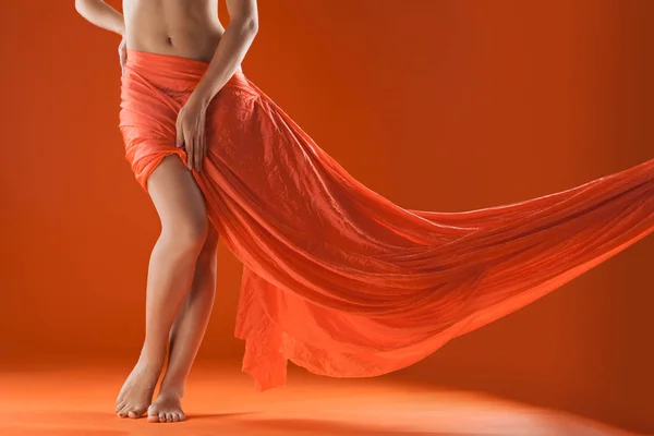 Beautiful female body with fabric loop on a orange background — Stock Photo, Image