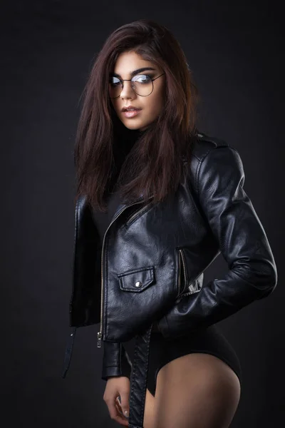 Brunette meisje in een zwarte lederen jas. Mooi model op een donkere achtergrond. — Stockfoto