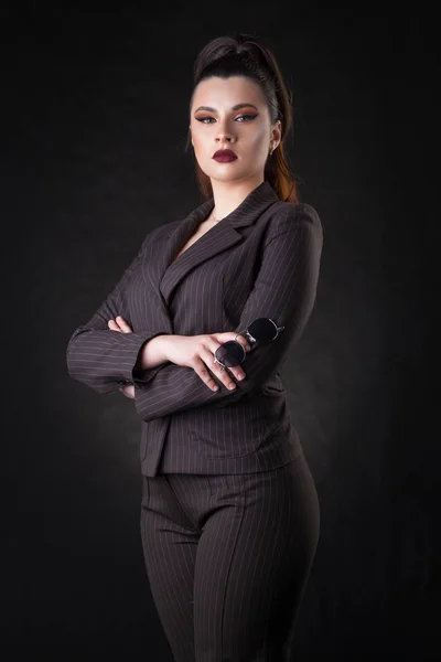 Glückliche junge Geschäftsfrau posiert vor dunklem Wandhintergrund. — Stockfoto