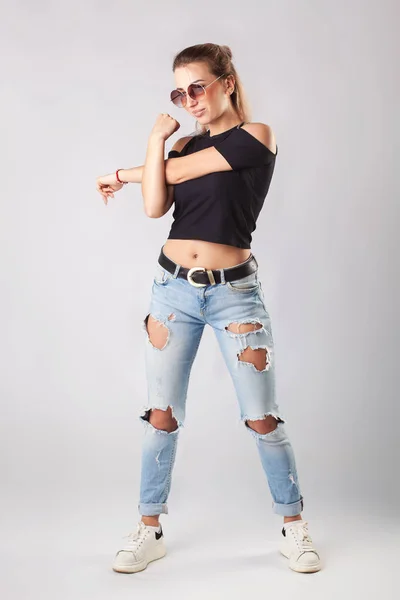 Lächelnde attraktive Frau in Jeans und T-Shirt posiert und blickt in die Kamera. — Stockfoto