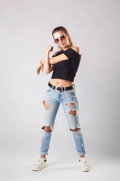 Mujer atractiva sonriente en jeans y camiseta posando y mirando a la cámara . — Foto de Stock