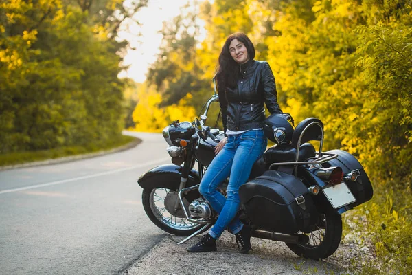 Attraktive brünette Motorradfahrerin sitzt auf einem Motorrad. — Stockfoto