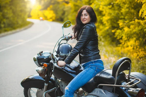 Attraktive brünette Motorradfahrerin sitzt auf einem Motorrad. — Stockfoto